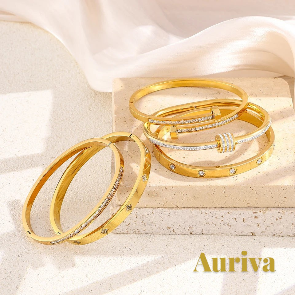 Gr8est Auriva gold titanium steel stacked bangles with pave cubic zirconia flower designs on a stone display