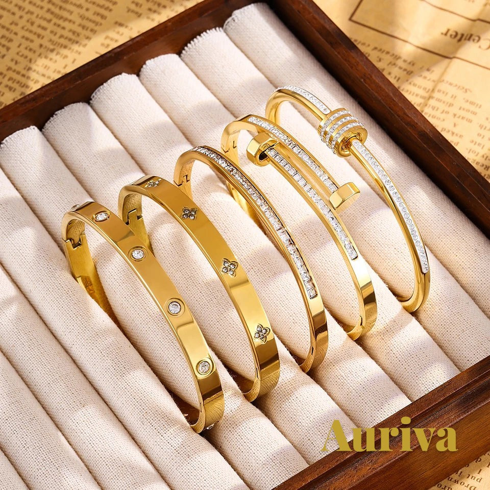 Gr8est Auriva gold titanium steel stacked bangles with cubic zirconia pave and flower motifs in a jewelry display box