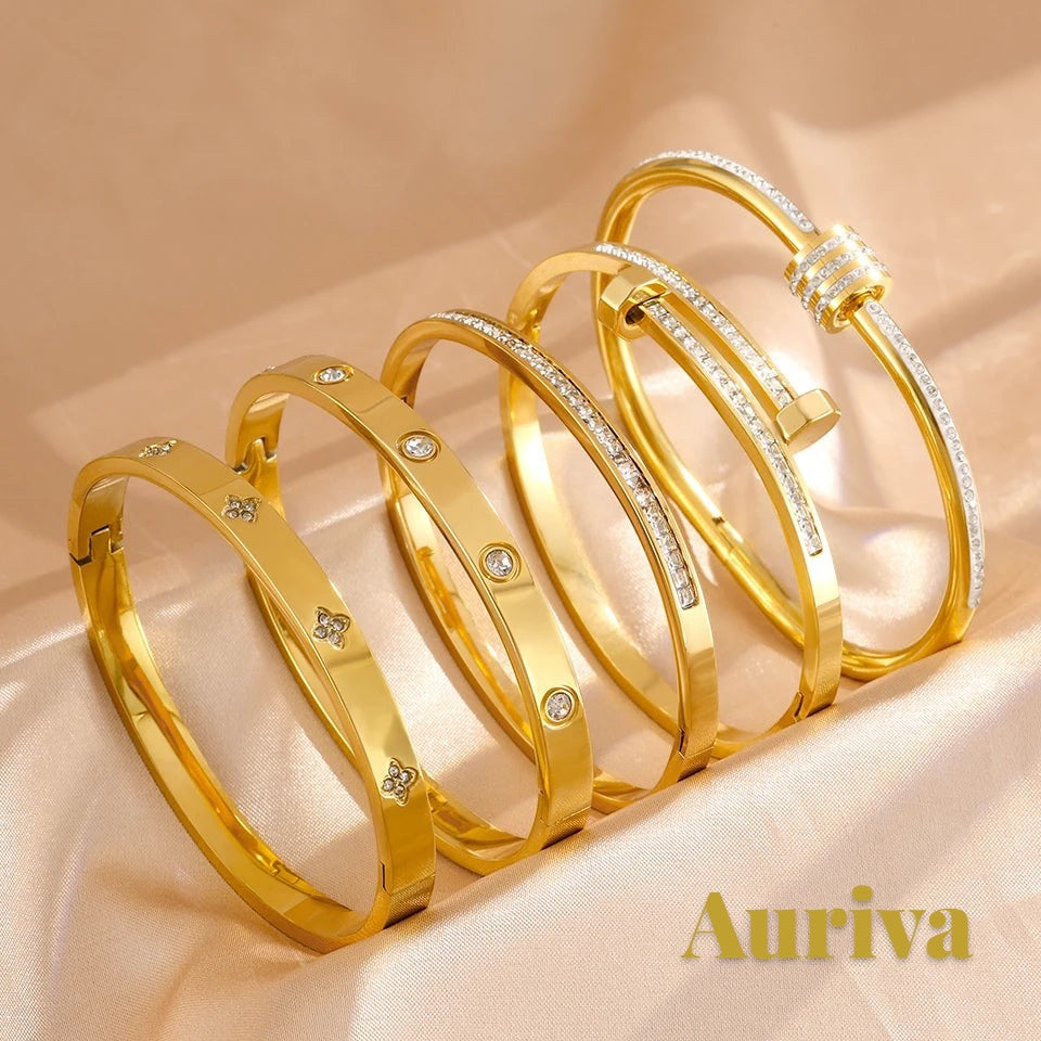 Gr8est Auriva gold titanium steel stacked bangles with pave cubic zirconia flower and nail designs on satin fabric.
