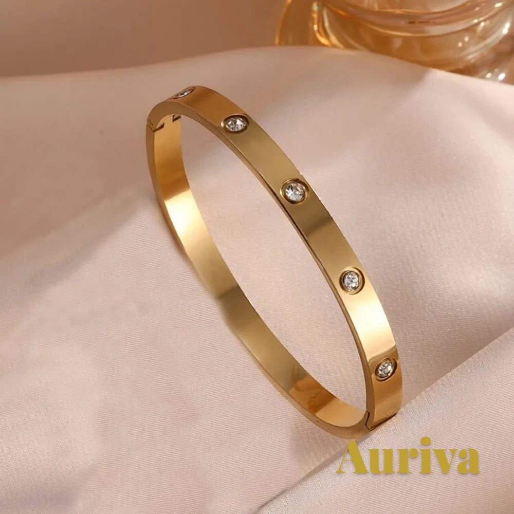Gr8est Auriva gold titanium steel bangle featuring embedded cubic zirconia stones on a soft satin background