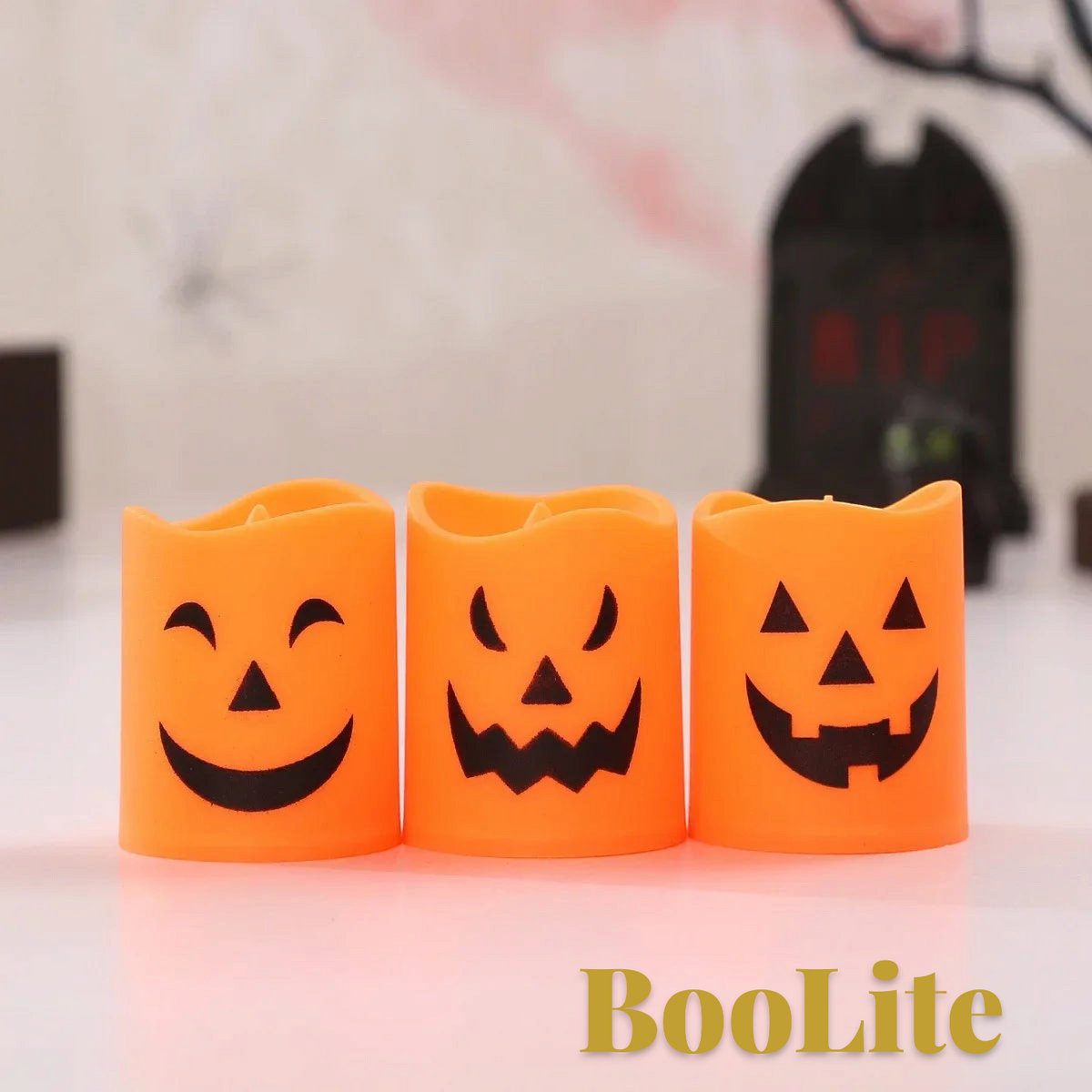 Gr8est BooLite set of three orange plastic LED Halloween candles with spooky jack-o-lantern faces on a white surface
