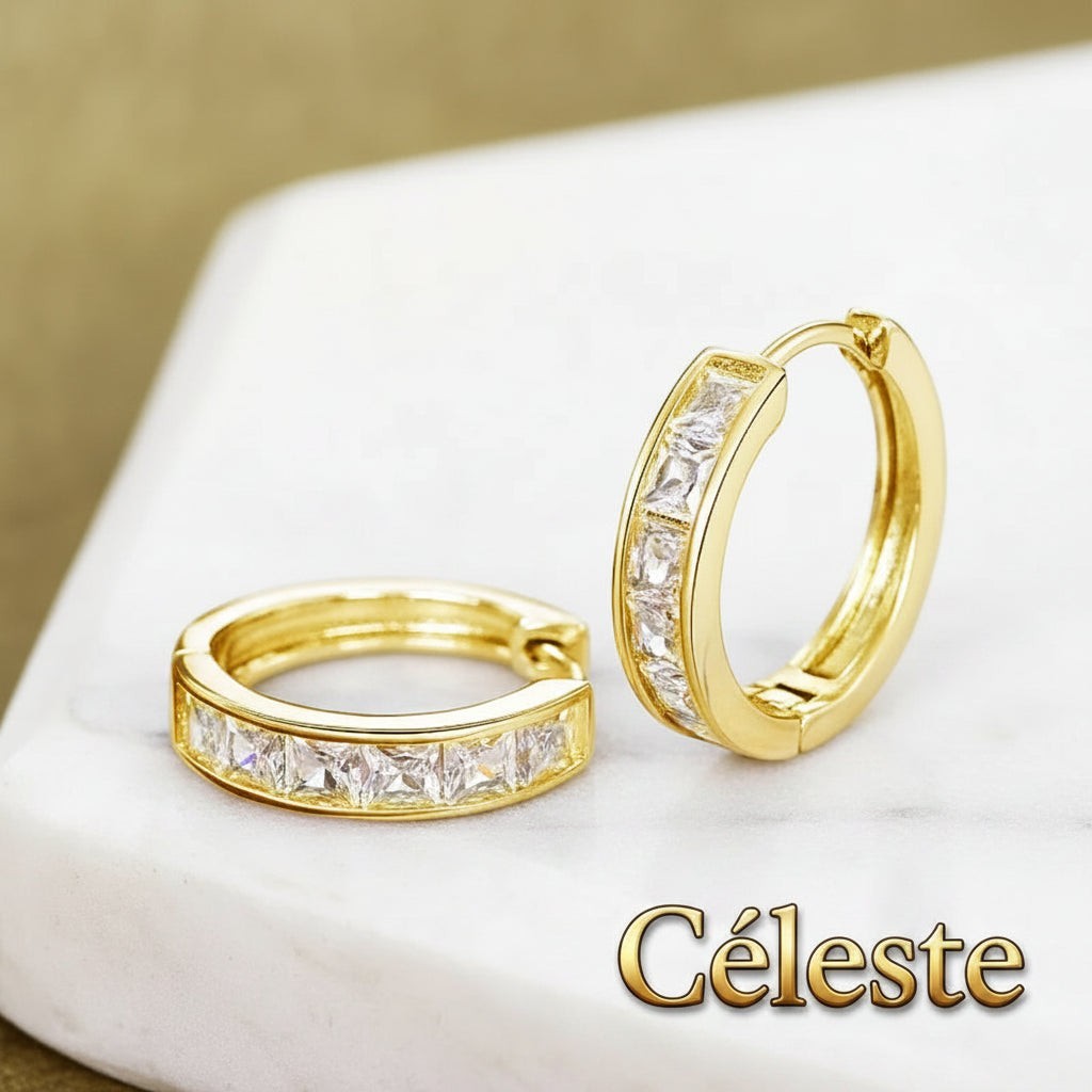 Gr8est Céleste gold-tone hoop earrings featuring princess-cut cubic zirconia stones on a white marble surface.