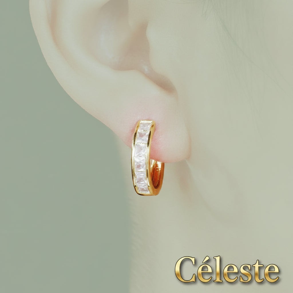 Gr8est Céleste gold-tone hoop earrings featuring princess-cut cubic zirconia stones worn on an earlobe.