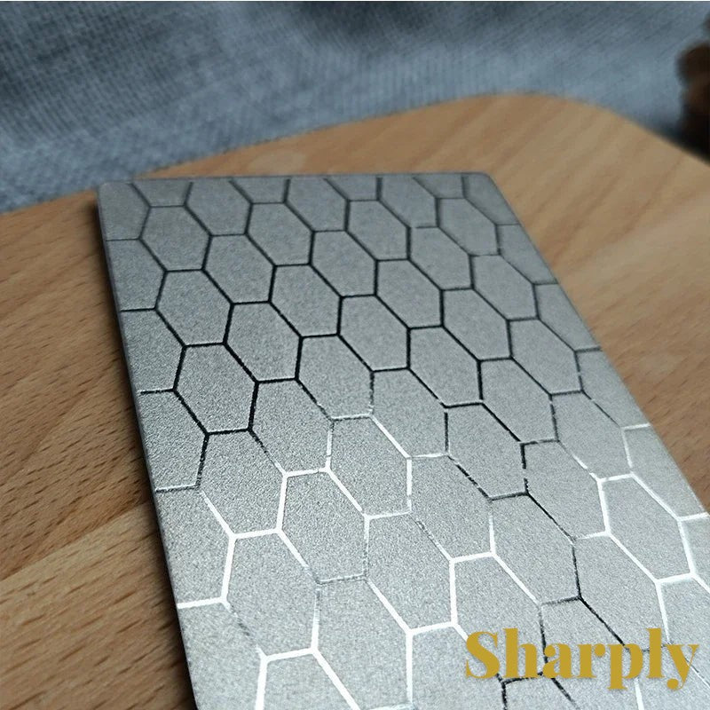 Gr8est diamond knife sharpening stone with a silver hexagonal pattern surface on a wooden board.