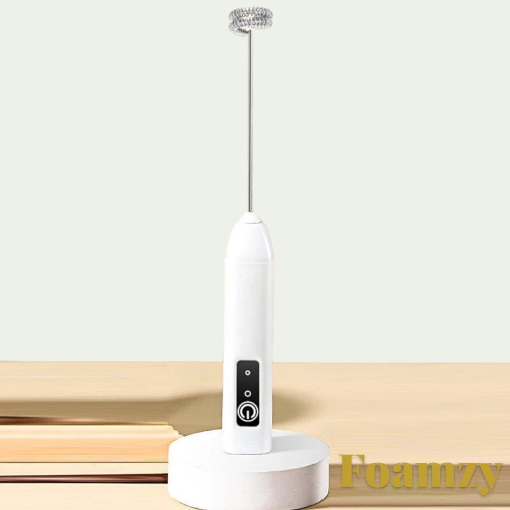 Gr8est Foamzy handheld electric milk frother and egg beater in white with a stainless steel whisk on a display stand.