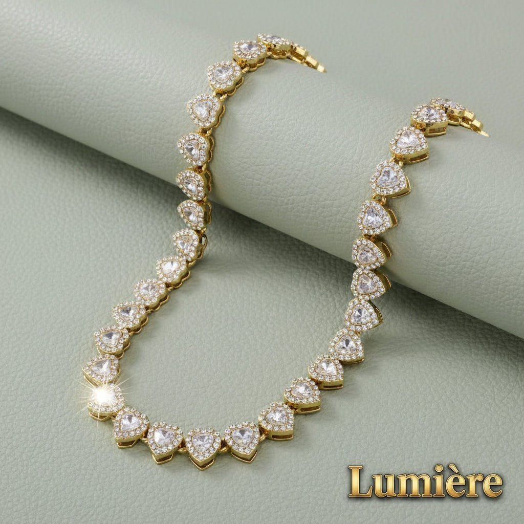 Gr8est gold-tone tennis necklace featuring a continuous row of sparkling heart-shaped rhinestones on a textured base.