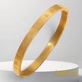 Gr8est gold stainless steel bangle bracelet featuring engraved Roman numerals on a white display pedestal