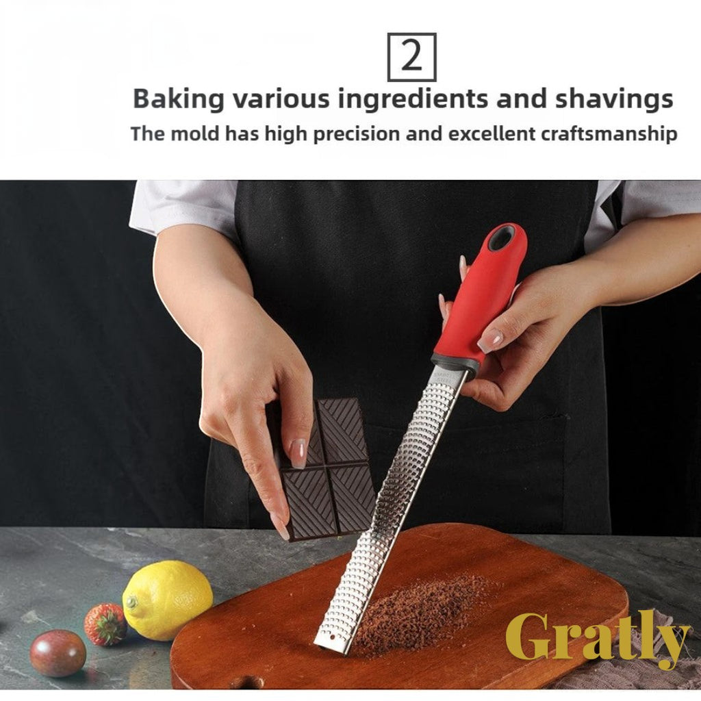 Gr8est Gratly stainless steel multi-purpose grater with a red ergonomic handle grating chocolate on a wooden board