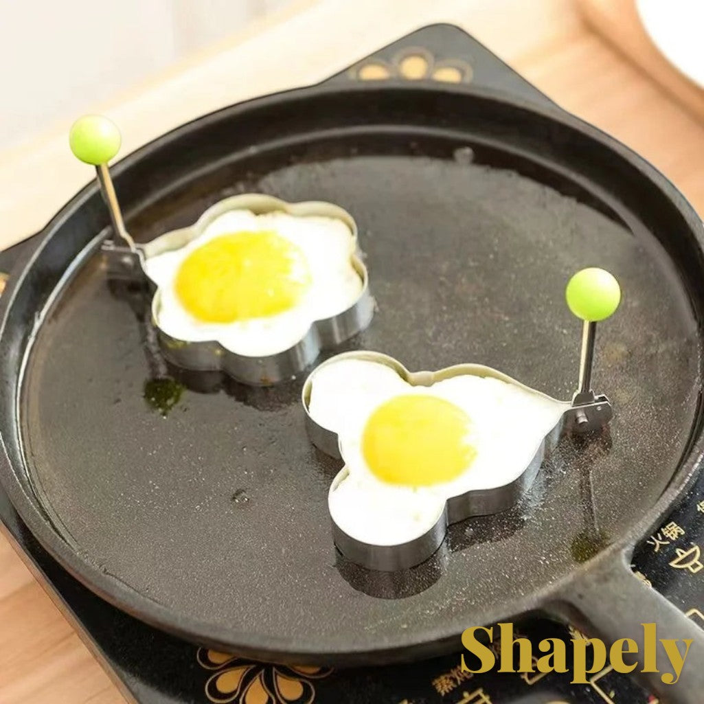 Gr8est stainless steel heart-shaped egg molds cooking fried eggs in a black frying pan