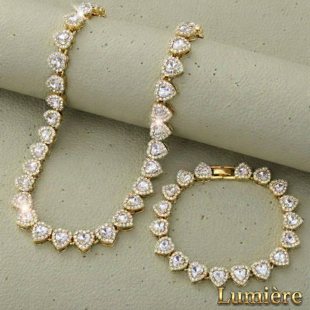 Gr8est Lumière gold-tone heart tennis necklace and bracelet set featuring sparkling rhinestones on a textured background.