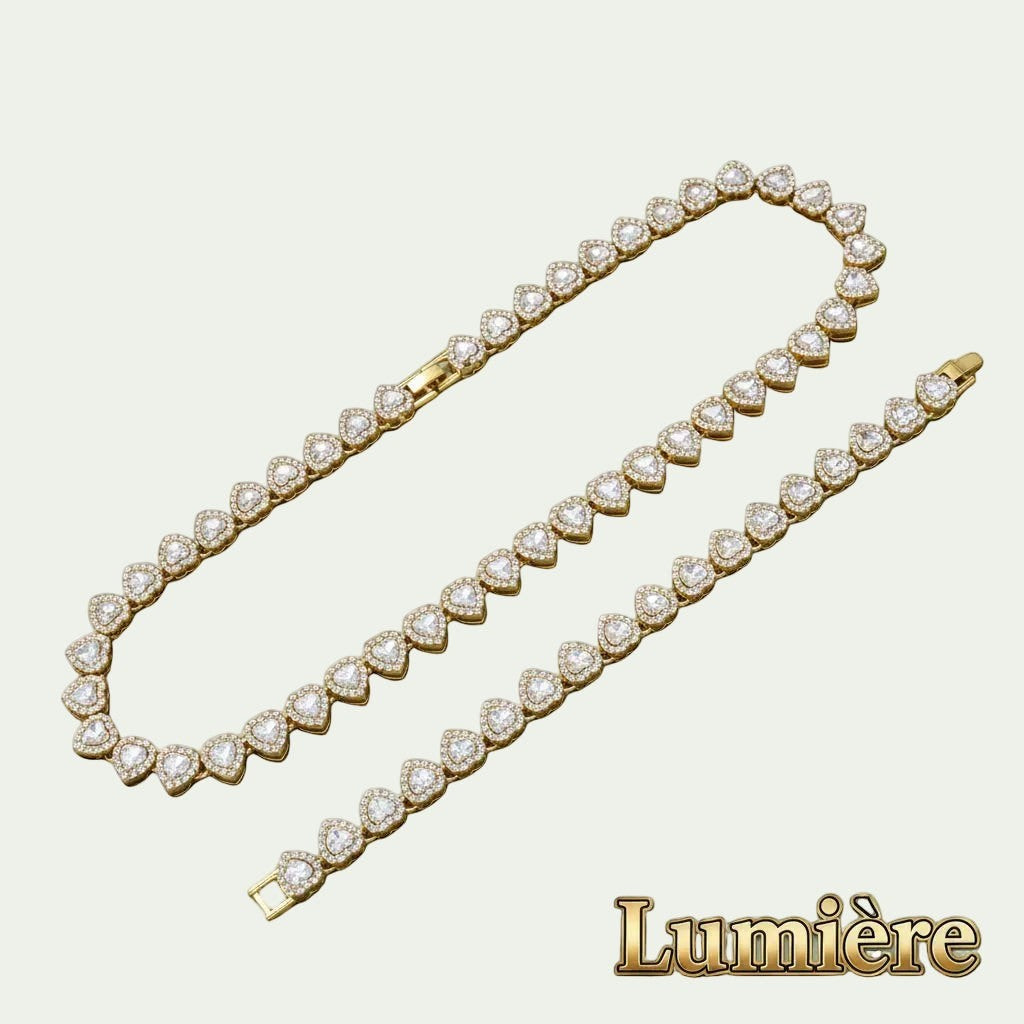 Gr8est Lumière gold heart tennis necklace and bracelet set with shimmering rhinestones in a zinc alloy metal finish.