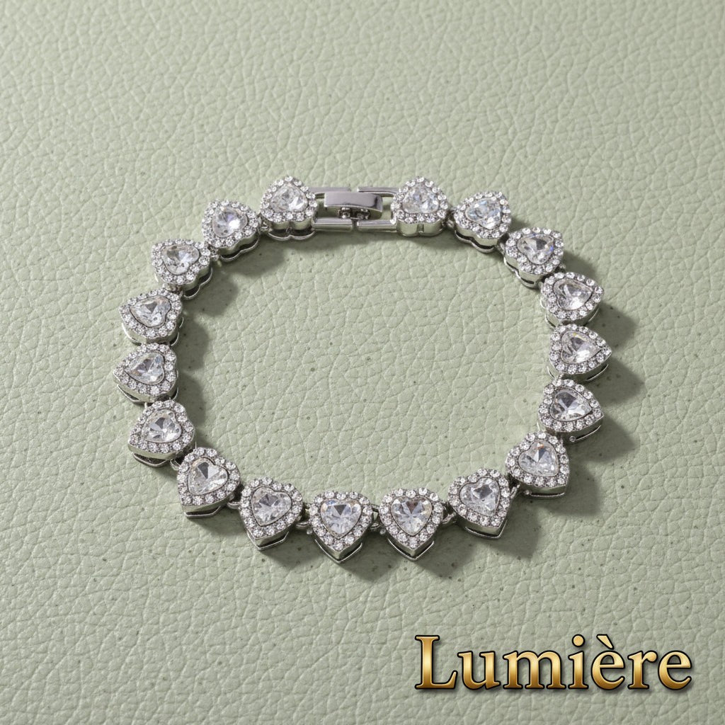 Gr8est Lumière silver heart tennis bracelet with sparkling rhinestones on a textured green background