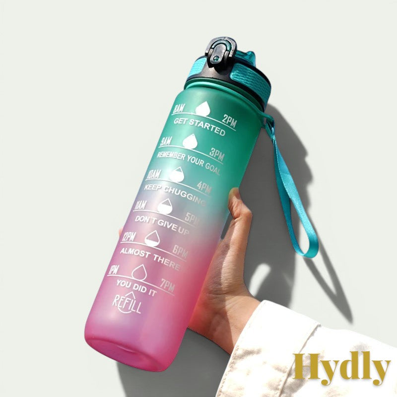 Gr8est 1L motivational water bottle in teal and pink gradient with time markers, straw, and carrying strap.