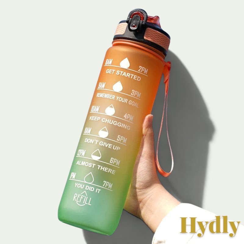 Gr8est 1L motivational water bottle in orange and green gradient with time markers and straw held against blue sky