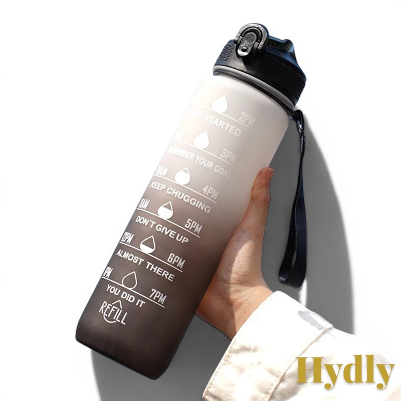 Gr8est 1L motivational water bottle in a black gradient finish with time markers, straw, and carrying strap.