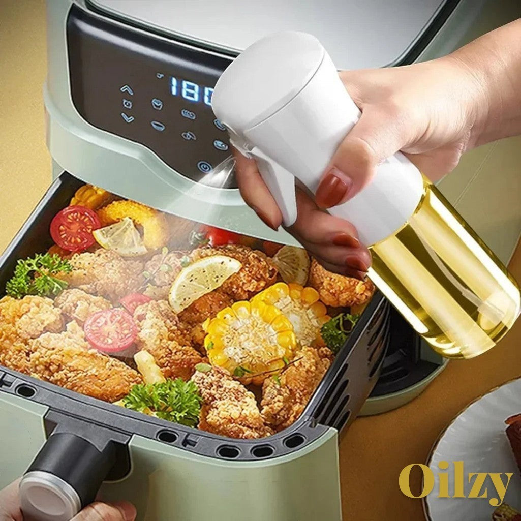Gr8est Oilzy kitchen oil spray bottle misting olive oil over fried chicken in an air fryer for healthy cooking.