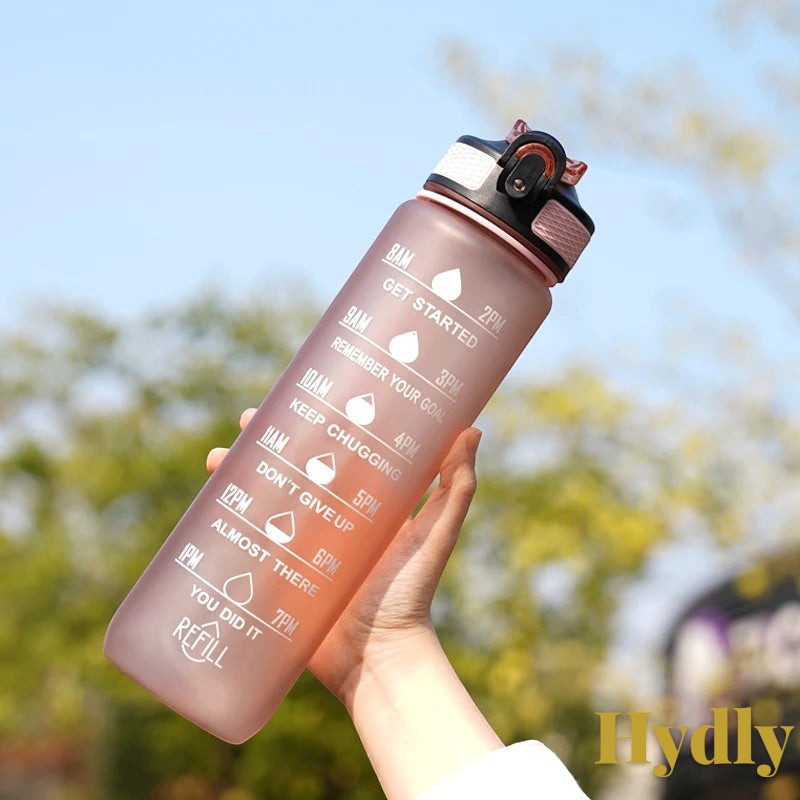 Gr8est 1L motivational water bottle in pink with time markers, straw, and leak-proof lid for gym and outdoor use.