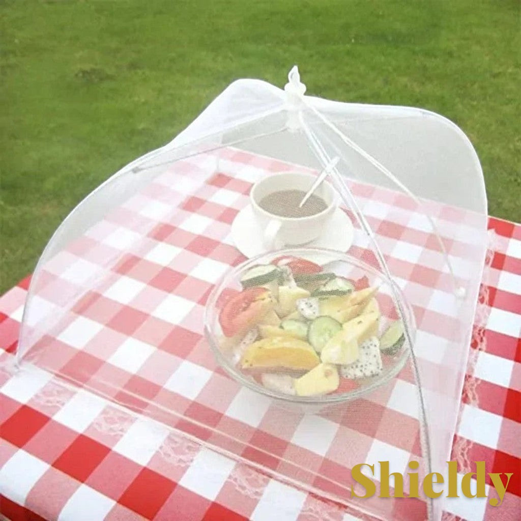 Gr8est white pop-up mesh food cover protecting a bowl of fruit on a red and white checkered picnic table outdoors