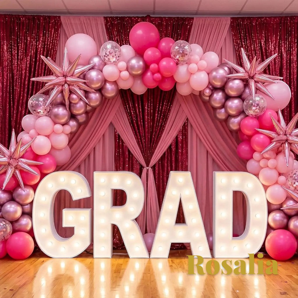 Gr8est Rosalia pink balloon arch kit with star and round latex balloons decorating a graduation party backdrop.