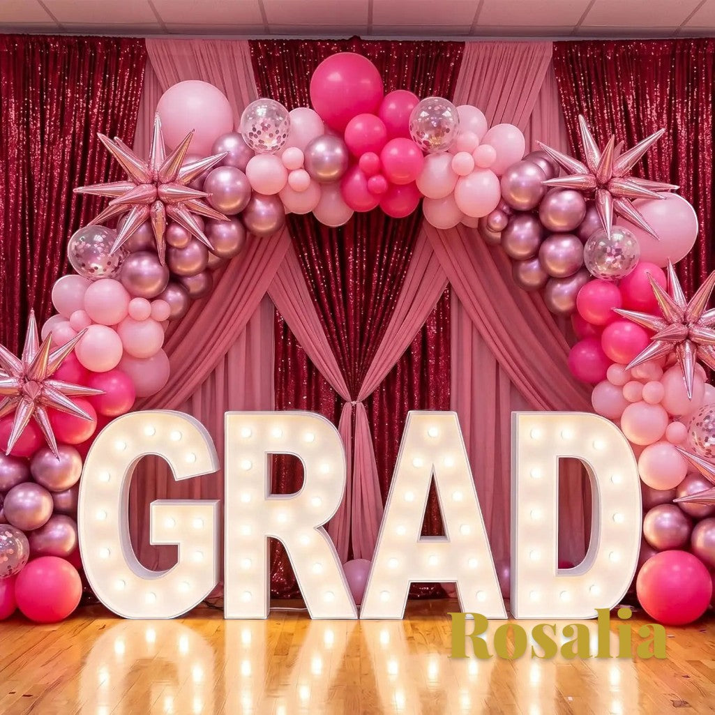 Gr8est Rosalia pink balloon arch kit with star and round latex balloons decorating a graduation party backdrop.