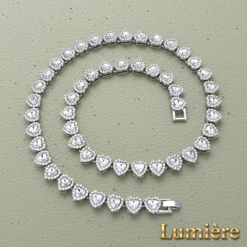 Gr8est silver heart tennis chain necklace and bracelet set with sparkling rhinestones on a textured green background.