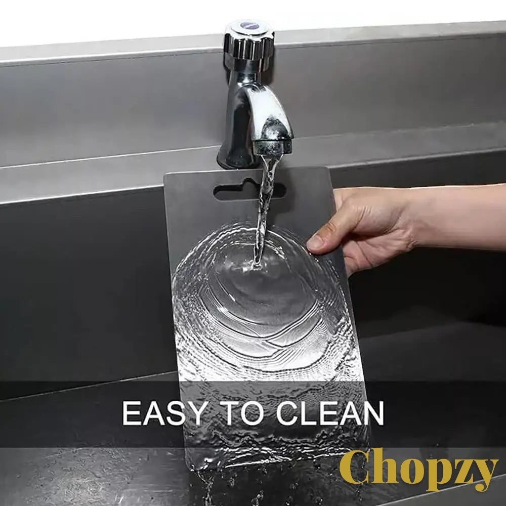 Gr8est Chopzy stainless steel cutting board being rinsed under a kitchen faucet for easy cleaning