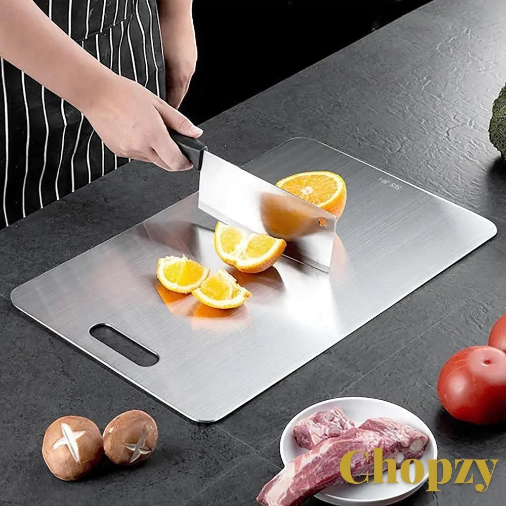 Gr8est stainless steel cutting board with a knife slicing an orange on a dark kitchen countertop