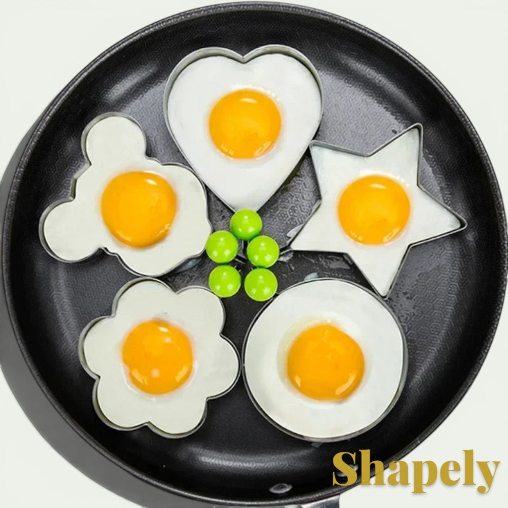 Gr8est stainless steel egg and pancake molds in heart, star, flower, and circle shapes cooking in a frying pan
