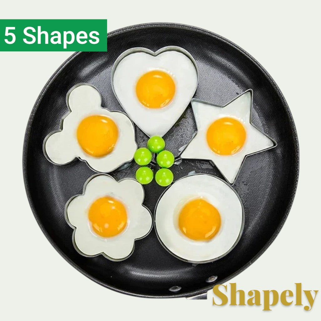 Gr8est 5-piece stainless steel egg and pancake mold set in heart, star, flower, and circle shapes in a frying pan.