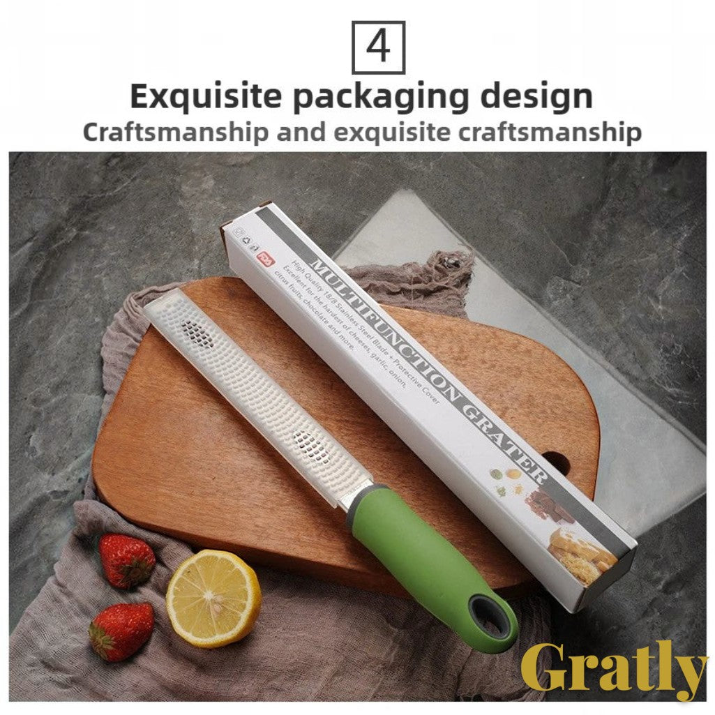 Gr8est stainless steel multi-purpose grater with a green ergonomic handle, shown with its packaging and fresh fruit.