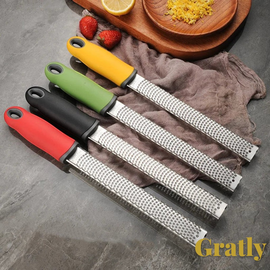 Gr8est stainless steel multi-purpose graters with red, black, green, and yellow ergonomic handles on a grey surface.