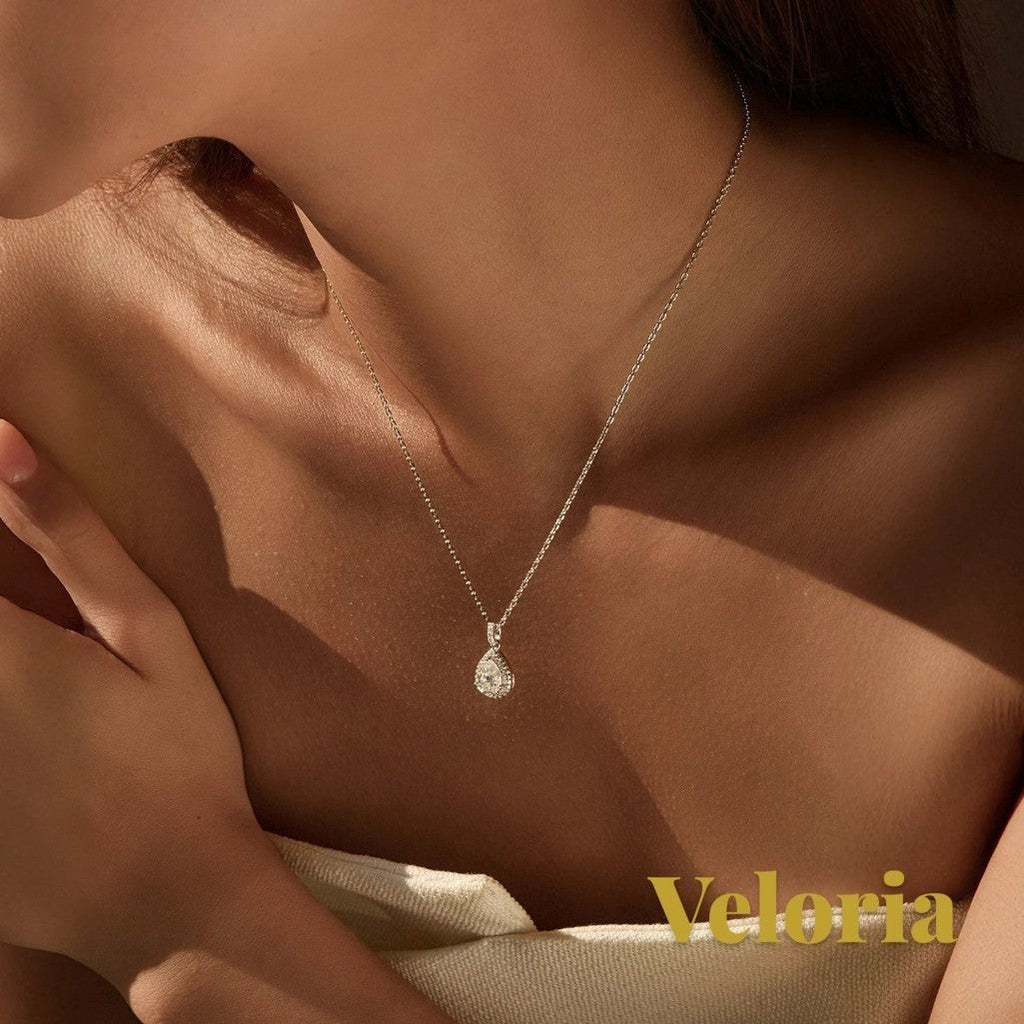 Gr8est Veloria 1.2CT water drop moissanite pendant necklace in 925 sterling silver worn on a woman's neck.